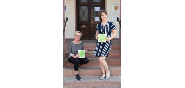 Monika Weber (Stadtmarketing) und Tanja Frisch (Wirtschaftsförderung Stadt Seligenstadt) mit Motivationsaufklebern für die Gastronomie und den Einzelhandel