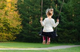 Mädchen auf Schaukel Kinder im Sandkasten