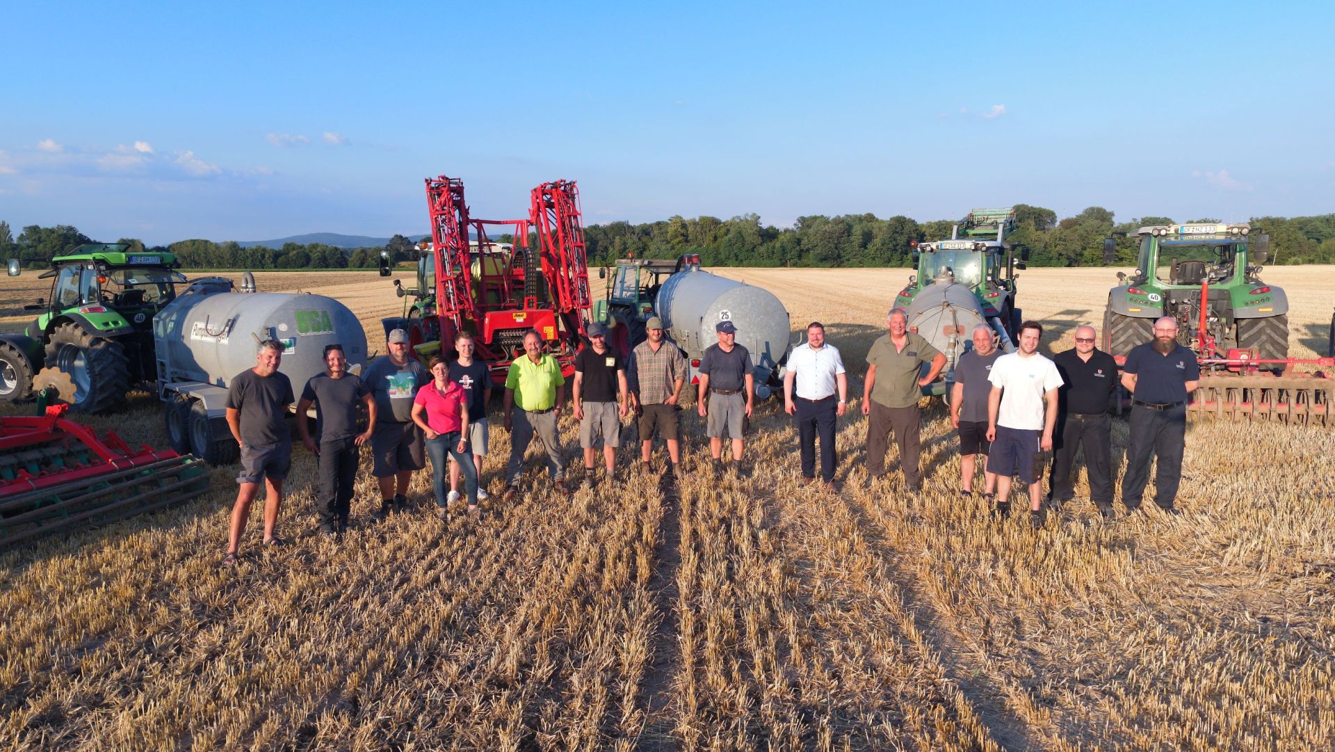 Ortsansässige Landwirte mit Stadtrat Steidl vor den Fasswagen und Traktoren mit Grubbern