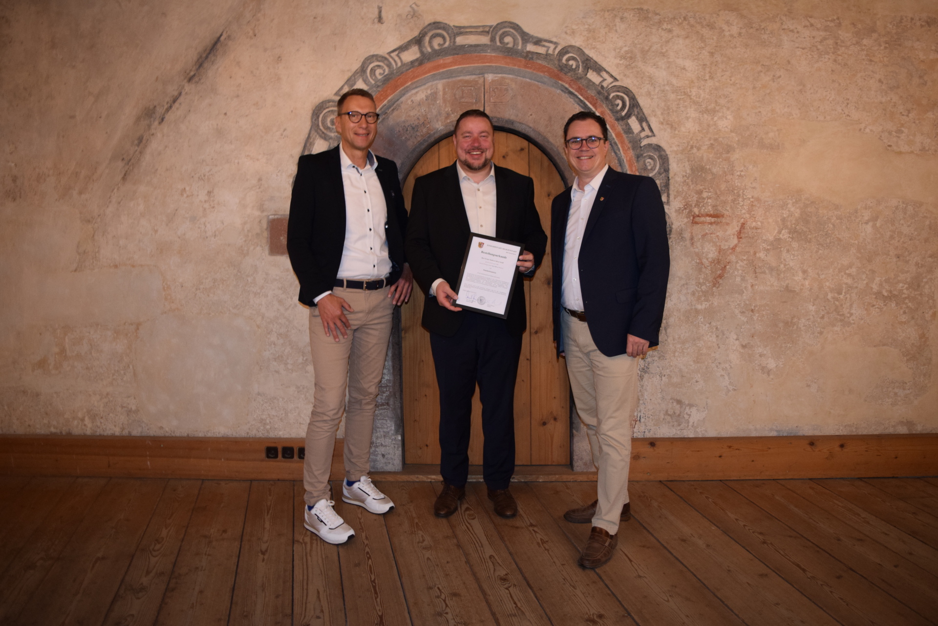 Standesamtsleiter Lange, Standesbeamter Steidl mit Bestellungsurkunde, Bürgermeister Dr. Bastian im Romanischen Haus Standesamtsleiter Lange, Standesbeamter Steidl mit Bestellungsurkunde, Bürgermeister Dr. Bastian im Romanischen Haus