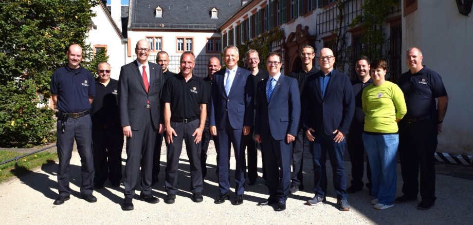 von links nach rechts vorne: Einsatzleiter Dr. Richard Georgi, Stadtbrandinspektor Alexander Zöller, Staatsminister Martin Rößler, Bürgermeister Dr. Daniell Bastian, stellv. Direktor Staatliche Schlösser und Gärten Hessen Volker Gilbert, Leiterin des Gartens und der Außenstelle Jana Lühring. Um die genannten Personen herum stehen ehrenamtliche und hauptamtliche Feuerwehrleute.